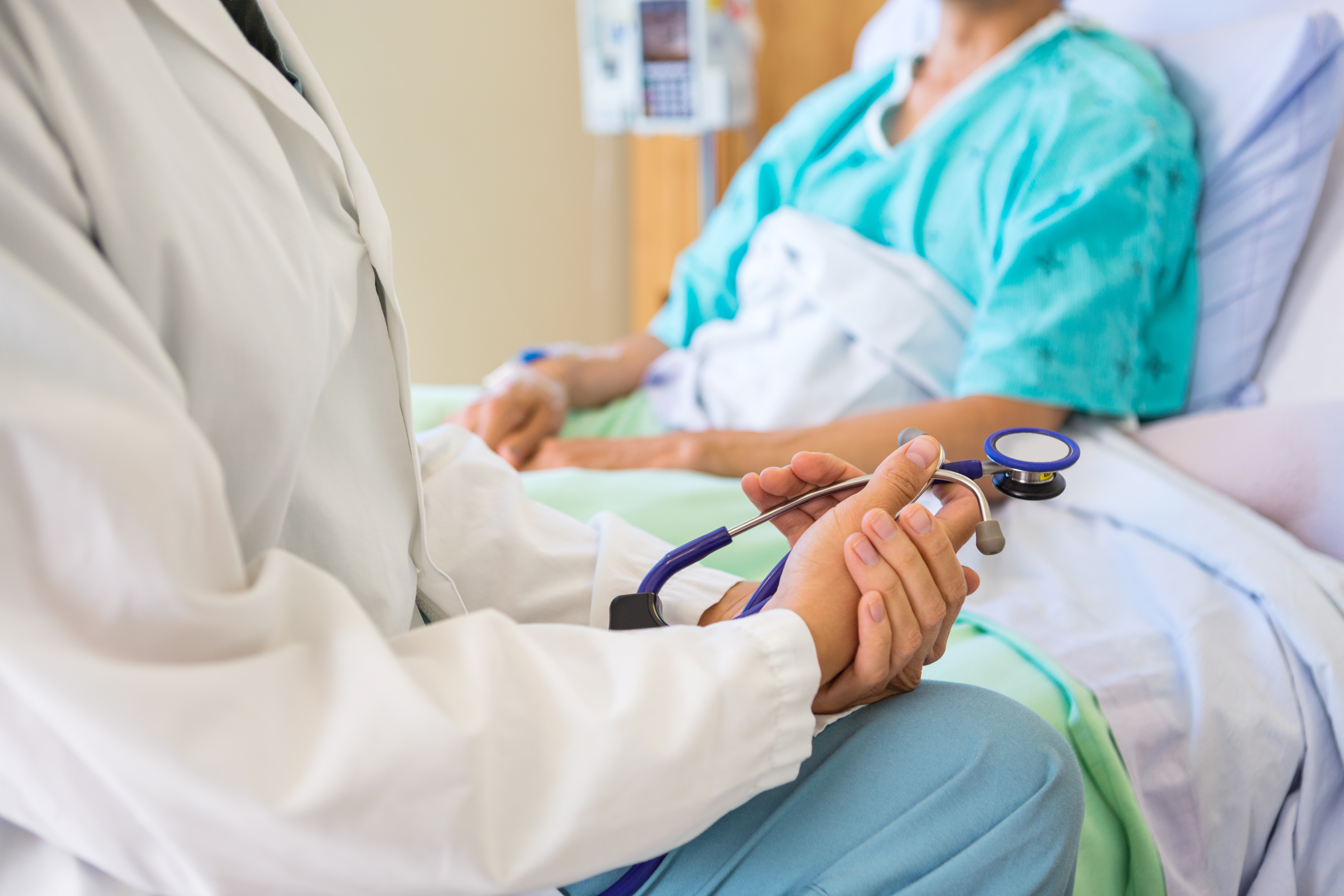 Female Doctor Sitting With Patient On Hospital Bed
